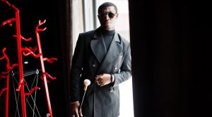 Stylish african american gentleman in elegant black jacket and sunglasses, holding retro walking stick as cane flask or tippling cane with golden diamond ball handle. Rich fashionable afro man.